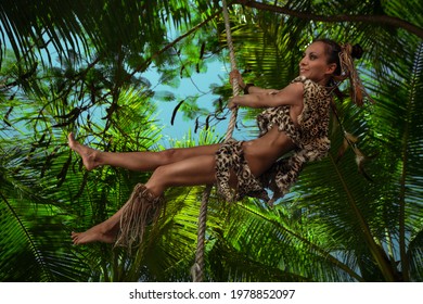 Female Tarzan Wearing In Leopard Fur Swinging On A Rope In Jungle 