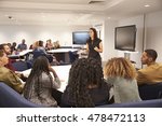 Female teacher addressing university students in a classroom