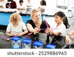 Female teacher with blonde hair helping diverse children with STEM activities. Children engaged in STEM, building with sticks. STEM learning in a classroom setting. Elementary school education.