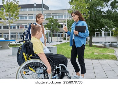 Female teacher and children, boy in wheelchair and girl talking outdoor - Powered by Shutterstock