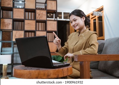 female teacher in civil servant uniform with hand gestures during online meeting using a laptop computer when working from home