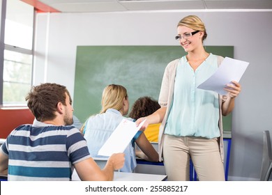 Female Teacher Handing Paper To Student In The Class