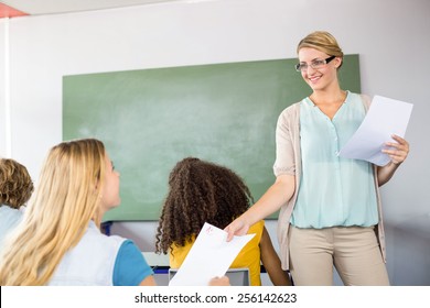 Female Teacher Handing Paper To Student In The Class