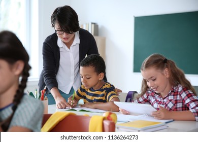 Female teacher helping child with assignment at school - Shutterstock ID 1136264273
