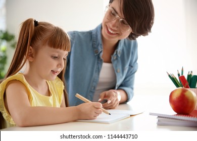 Female Teacher Helping Child With Assignment At School