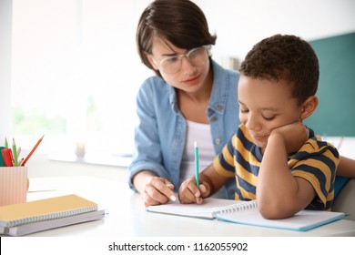 Female Teacher Helping Child With Assignment At School