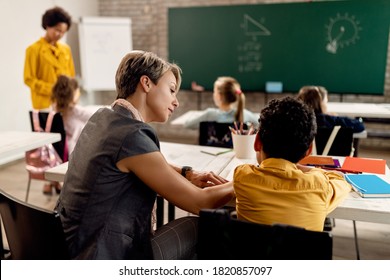 Female teacher helping elementary student with studying in the classroom.  - Shutterstock ID 1820857097