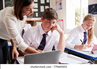 Female Teacher Helping Pupil Using Computer In Classroom