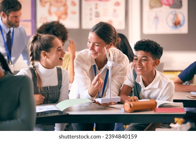 Female Teacher Helping Secondary Or High School Students Studying Wind Turbines In Science Class - Powered by Shutterstock