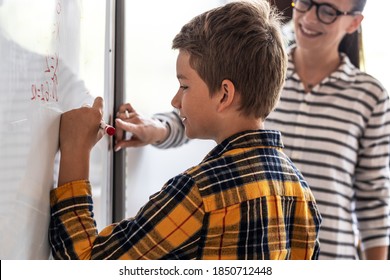 Female teacher helps her student to resolve mathematics problem on school board.	
 - Powered by Shutterstock