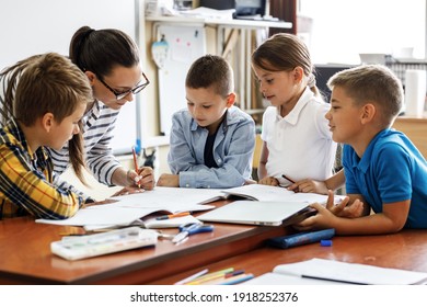 Female teacher helps school kids to finish they lesson.They sitting all together at one desk.	
 - Powered by Shutterstock