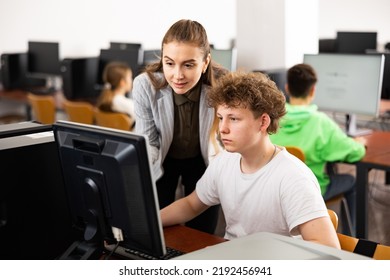 Female Teacher And Her Student, Teenage Boy, Looking At Monitor Of PC During Computer Science Lesson.