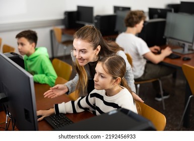 Female Teacher And Her Student, Young Girl, Looking At Monitor Of PC During Computer Science Lesson.