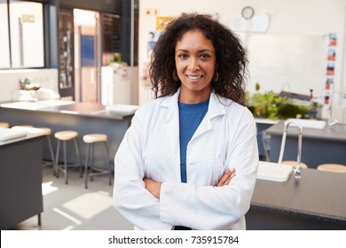 Female Teacher In Lab Coat Smiling In School Science Room