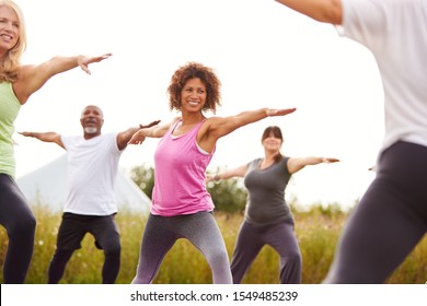 Female Teacher Leading Group Of Mature Men And Women In Class At Outdoor Yoga Retreat