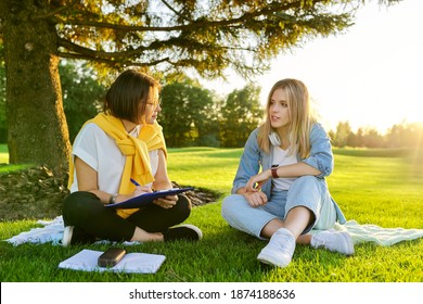 Female teacher psychologist social worker talking to teenage student on the lawn in the park. Sociology, psychology, education, youth concept