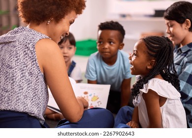 Female Teacher Reads To Multi-Cultural Elementary School Pupils Sitting On Floor In Class At School - Powered by Shutterstock