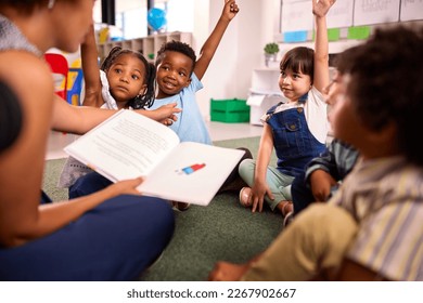 Female Teacher Reads To Multi-Cultural Elementary School Pupils Sitting On Floor In Class At School - Powered by Shutterstock