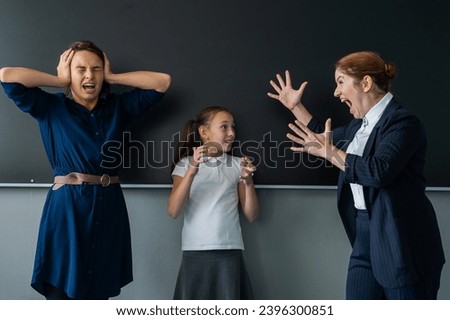 The female teacher screams at the schoolgirl and her mother standing at the blackboard. 