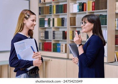 Female teacher talking to teenage girl high school student, inside educational building - Powered by Shutterstock