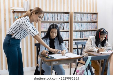 female teacher is teaching girls in class. School children education in classroom. kid schoolgirl happy learning. Writing as instructed by teacher. concept of back to school. - Powered by Shutterstock