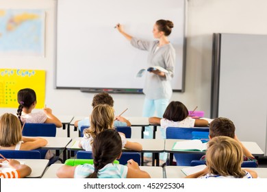 Female Teacher Teaching Schoolchildren In Classroom