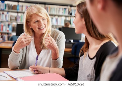 Female Teacher Working With College Students In Library