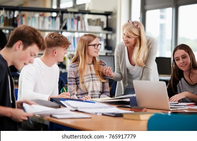Female Teacher Working With College Students In Library