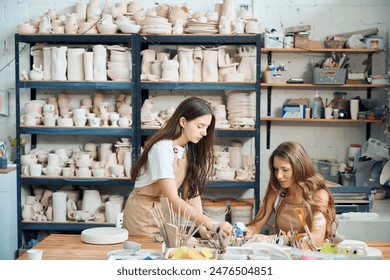 Female teaching young woman to work with clay making ceramic plate - Powered by Shutterstock