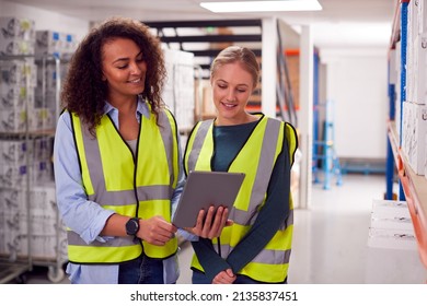 Female Team Leader With Digital Tablet In Warehouse Training Intern Standing By Shelves