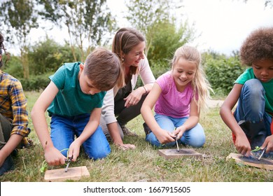 Female Team Leader Showing Group Of Children On Outdoor Camping Trip How To Make Fire