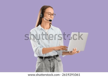 Female technical support agent in headset working with laptop on lilac background