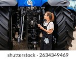 Female technician inspecting agricultural machinery and managing farm equipment repair with digital tablet