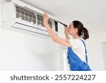 Female technician repairing air conditioner at home