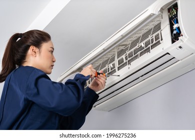 Female Technician Service Using Screwdriver To Repairing The Air Conditioner Indoors