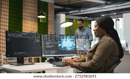 Female technician using computer to write code, developing machine learning APIs. African american woman troubleshooting software errors and faults using artificial intelligence, camera A