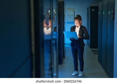 Female technician using laptop to analyze server in data center