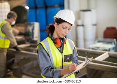 Female technician writing on clipboard in oil factory - Powered by Shutterstock