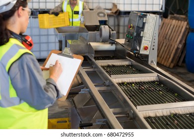 Female technician writing on clipboard in oil factory - Powered by Shutterstock