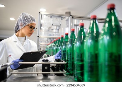 Female technologist working in bottling factory controlling production of drinking water and packaging. - Powered by Shutterstock