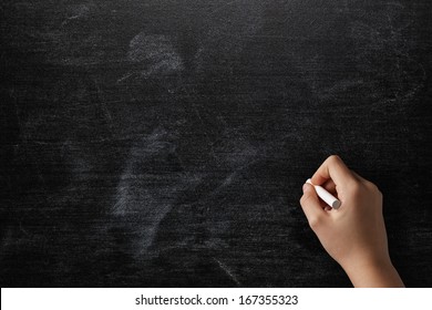 female teen hand to draw something on blackboard with chalk
