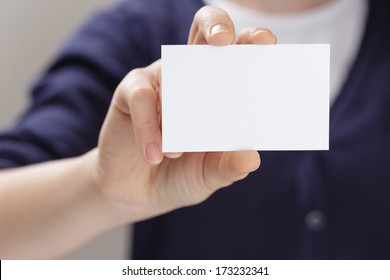 Female Teen Holding Empty Business Card In Front Of Camera, Blurred Background