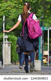 Female Teen Student With Bookbag Walking On Sidewalk