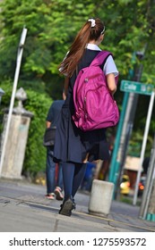 Female Teen Student With Bookbag Walking On Sidewalk