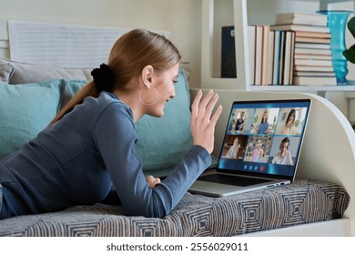 Female teenage student having group video conference, using digital tablet, lying on couch at home. - Powered by Shutterstock