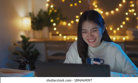Female teenager attending university online class during lockdown at night, participate in class using laptop answer the questions in living room at home