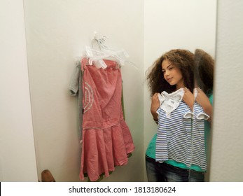 A Female Teenager In Front Of A Mirror Trying Out New Clothes In The Trial Room.