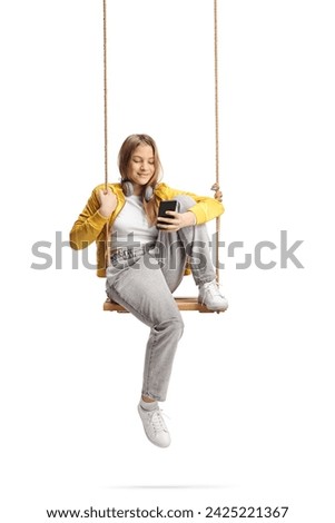 Female teenager sitting on a swing and looking at a smartphone isolated on white background