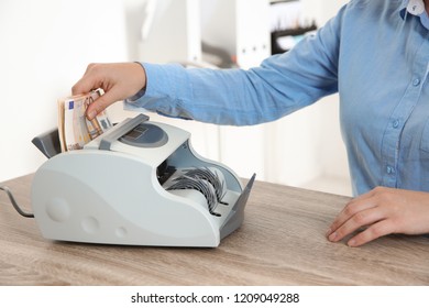 Female Teller Putting Money Into Currency Counting Machine At Cash Department, Closeup