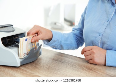 Female Teller Putting Money Into Currency Counting Machine At Cash Department, Closeup